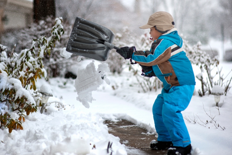 A small boy shovelling snow